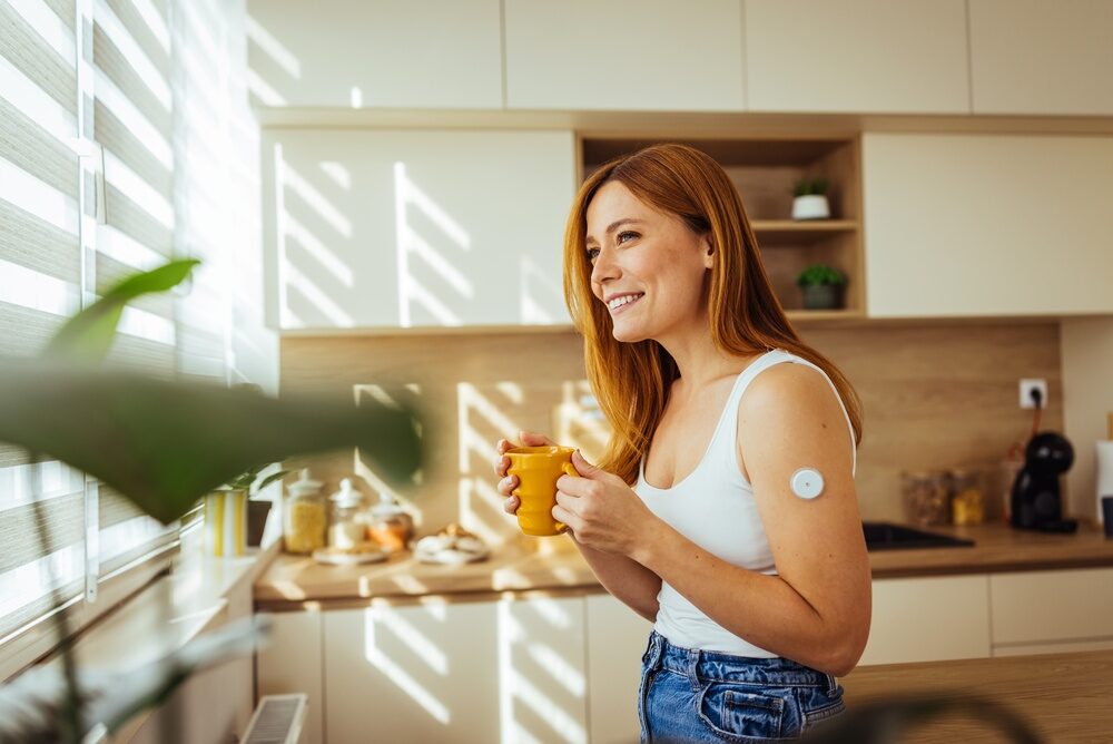 Smiling,Young,Woman,Stands,In,A,Sunlit,Kitchen,Holding,A